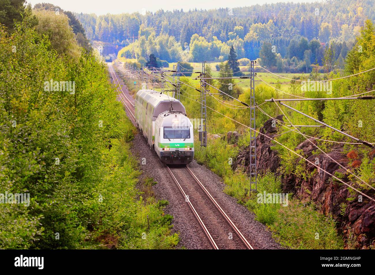 Grüne Frühherbstlandschaft mit VR Intercity Zug in Geschwindigkeit, Tunnel im Hintergrund. Salo, Finnland. 29. August 2021. Stockfoto