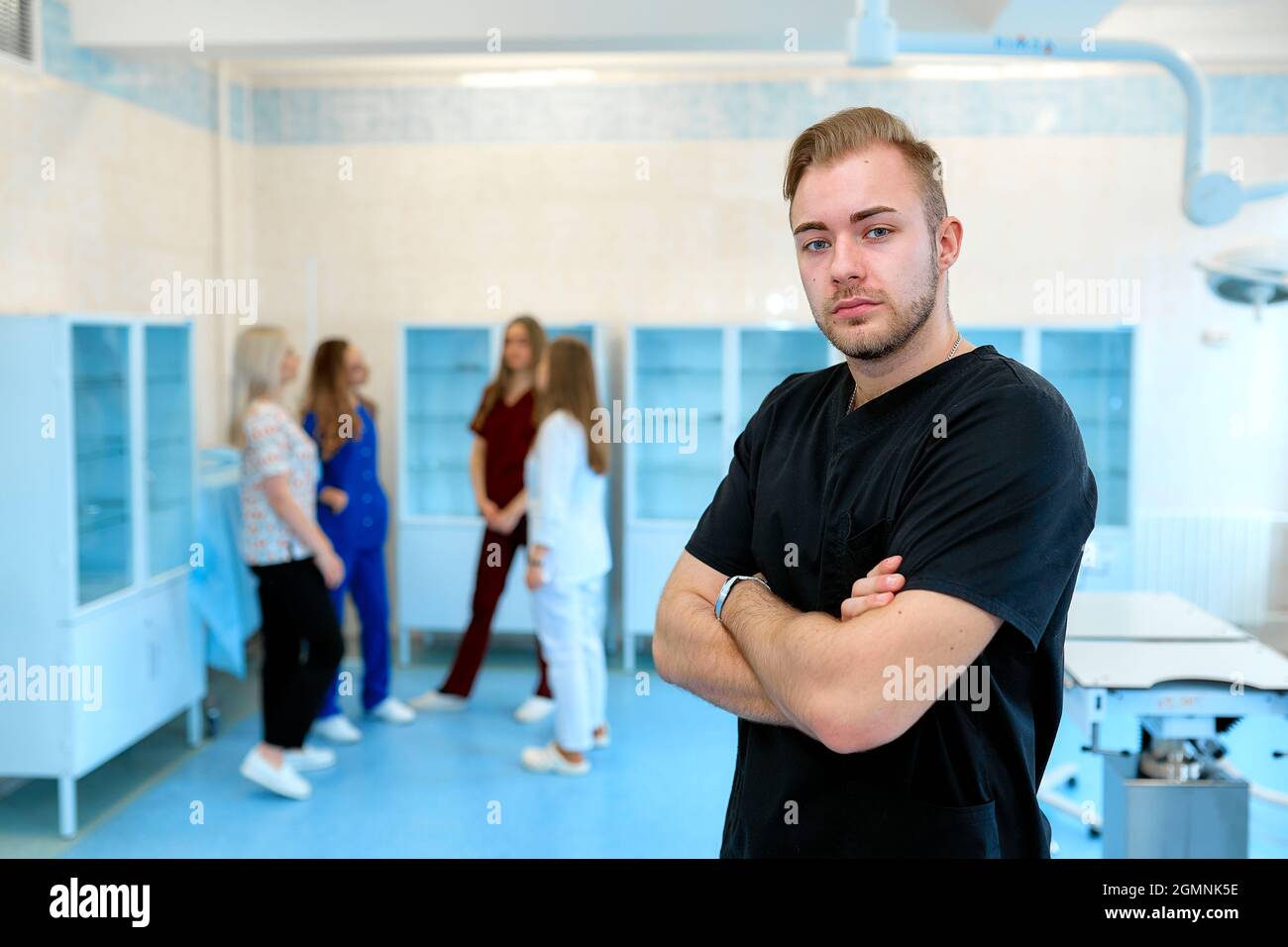 Ein Foto eines männlichen Arztes, der sitzt und lächelt, während seine Kollegen im Hintergrund stehen. Stockfoto