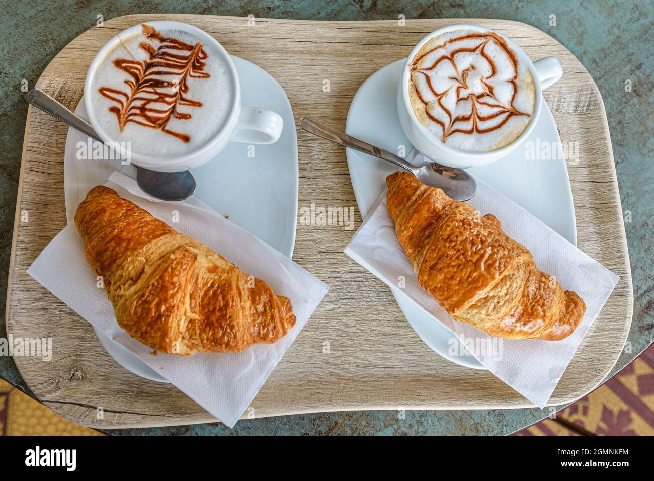 Blick von oben auf das Frühstück mit Croissant und Cappuccino in einem italienischen Café in der Schweiz. Reisen Schweiz im Kanton Tessin. Stockfoto