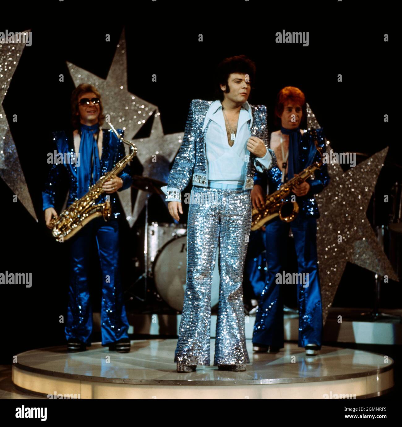 Garry Glitter, geboren als Paul Francis Gadd, bekannt auch als Paul Raven, britischer Glamrock Musiker, bei einem Auftritt mit Band um 1974. Der in Garry Glitter geborene Paul Francis Gadd, auch bekannt als Paul Raven, britischer Glam-Rock-Musiker, trat um 1974 mit der Band auf. Stockfoto