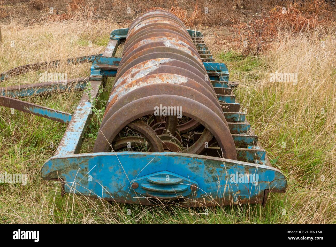 Schwere Landmaschinen Scheibenegge auf einer grasbewachsenen Feldgrenze geparkt Stockfoto