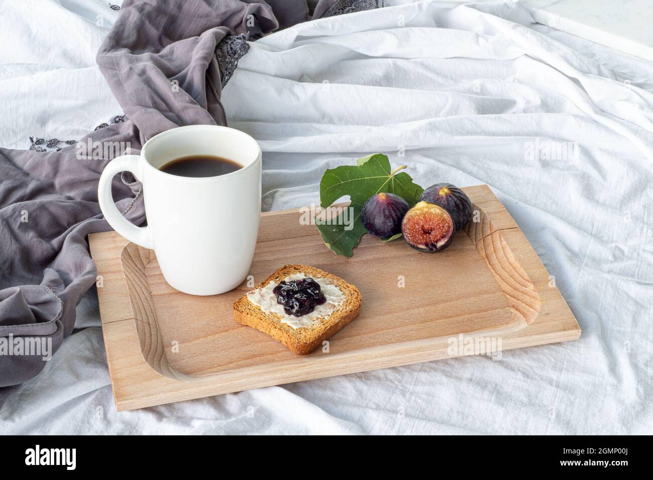Herbstfrühstück Stillleben. Tasse Kaffee, Feigenfrucht, Brot mit Butter und Marmelade auf Holzbrettchen. Frühstück im Bett, Herbstkost-Konzept. Stockfoto