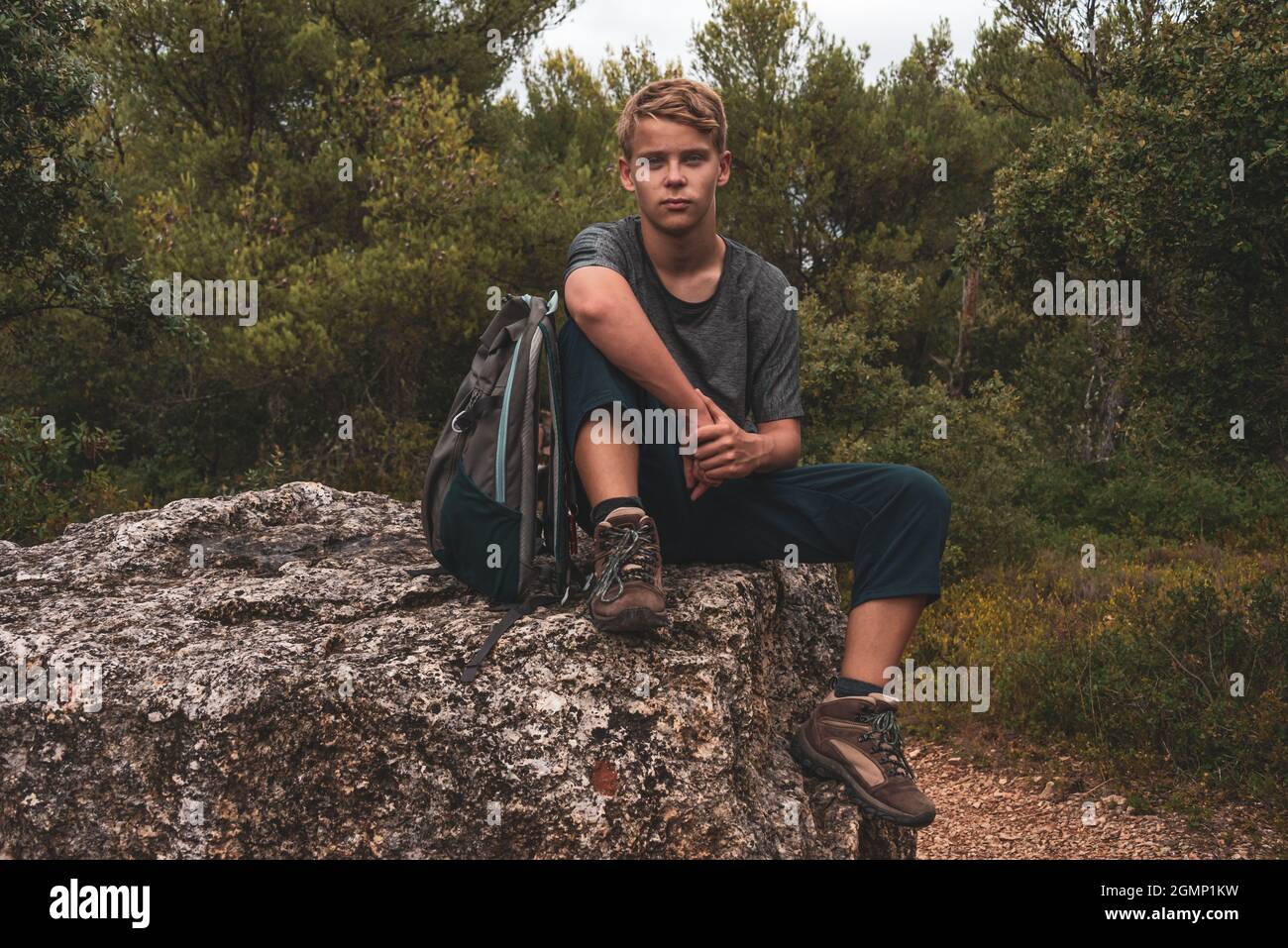 Junger Mann Wanderer ruht auf großen Felsen in der französischen Landschaft, Abenteuer Wanderurlaub. Stockfoto