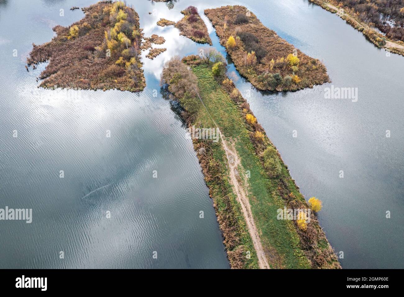 Schöne Herbstlandschaft. Fluss mit ruhigem Wasser und Wolken Reflexionen. Kleine Inseln mit bunten Bäumen. Luftdrohne Foto Stockfoto