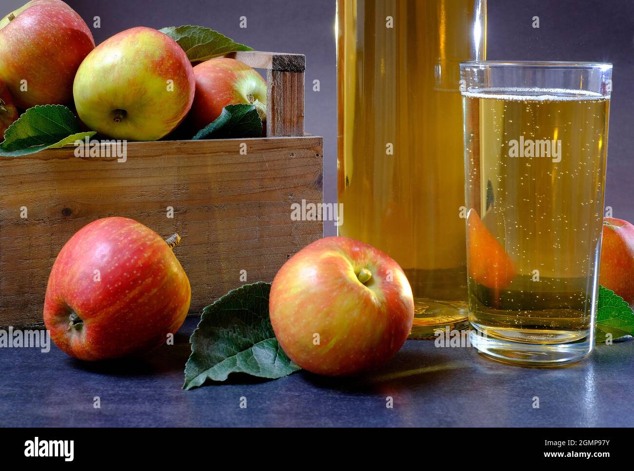 Flasche und Glas Apfelwein mit Äpfeln in Holzkiste Stockfoto