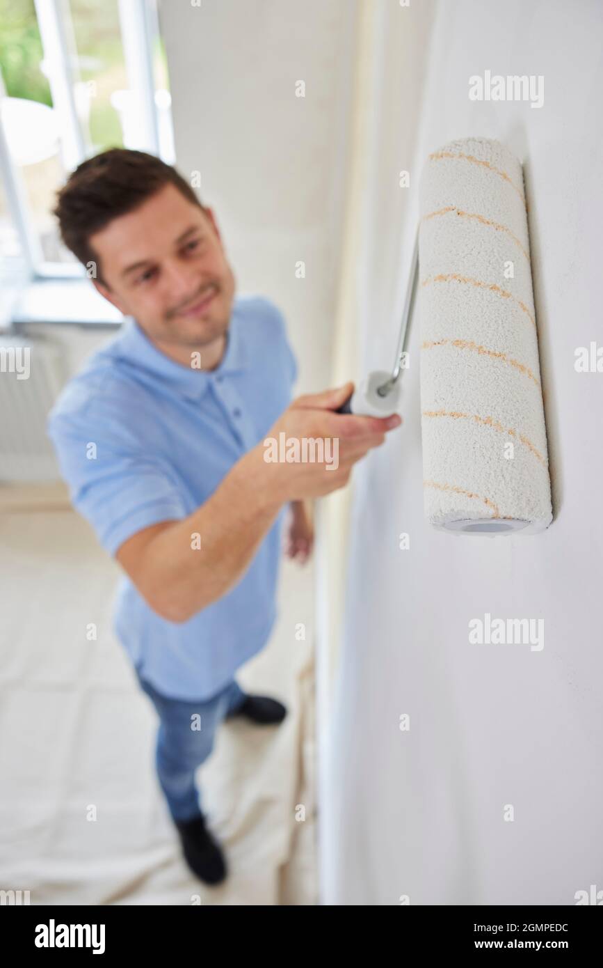 Mann Malt Wand Im Zimmer Des Hauses Mit Malrolle Stockfoto