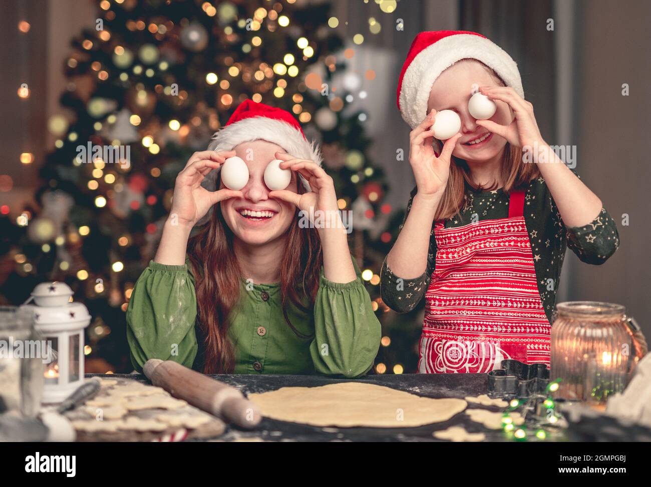 Glückliche Freundinnen in weihnachtsmützen mit Eiern Stockfoto