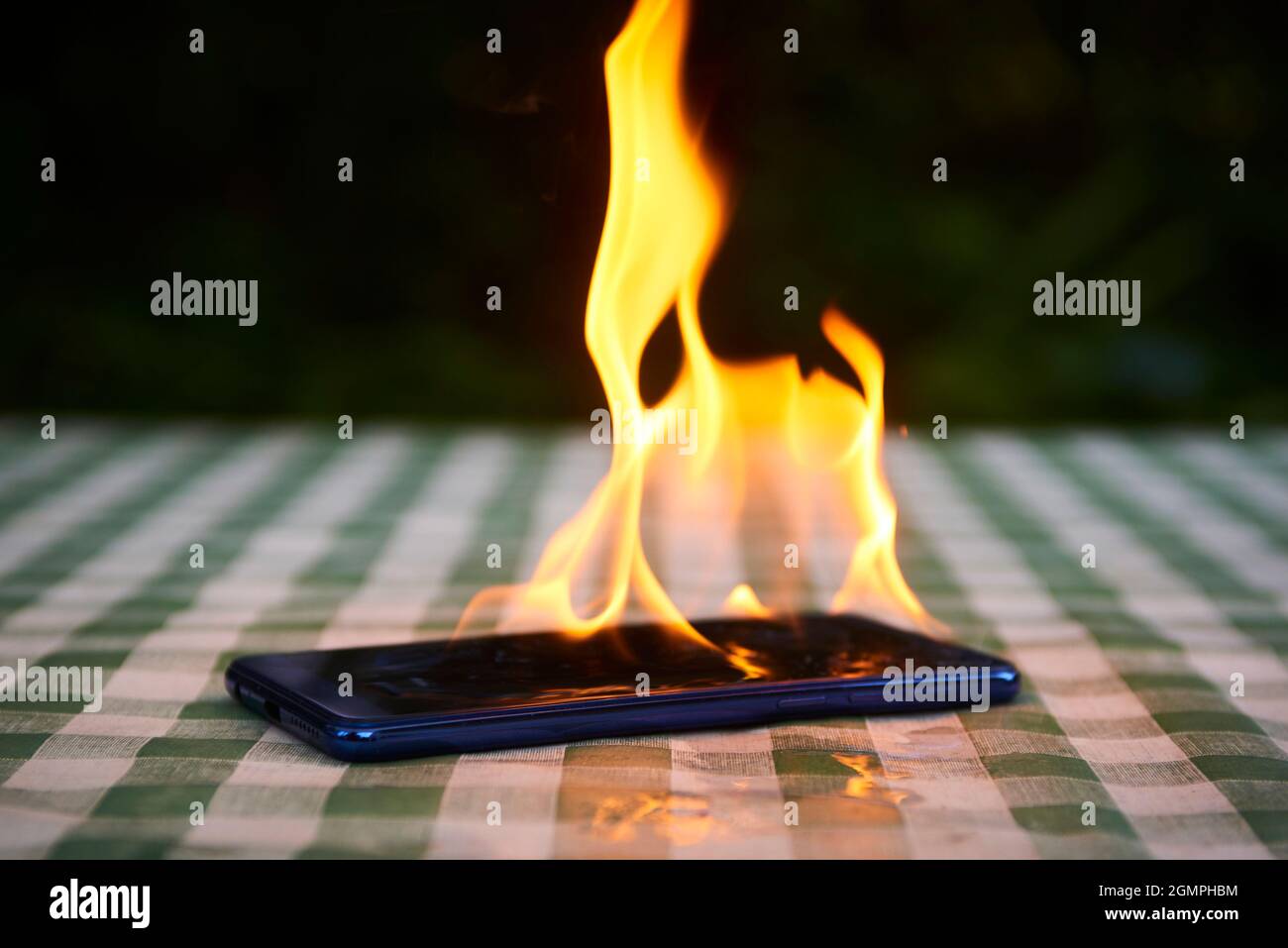 Handy explodiert und brennt. Explosion und Brand von Mobiltelefonen. Gefahr für Smartphones durch Übernutzung oder schlechte Herstellung. Überhitzung wird verbrannt Stockfoto