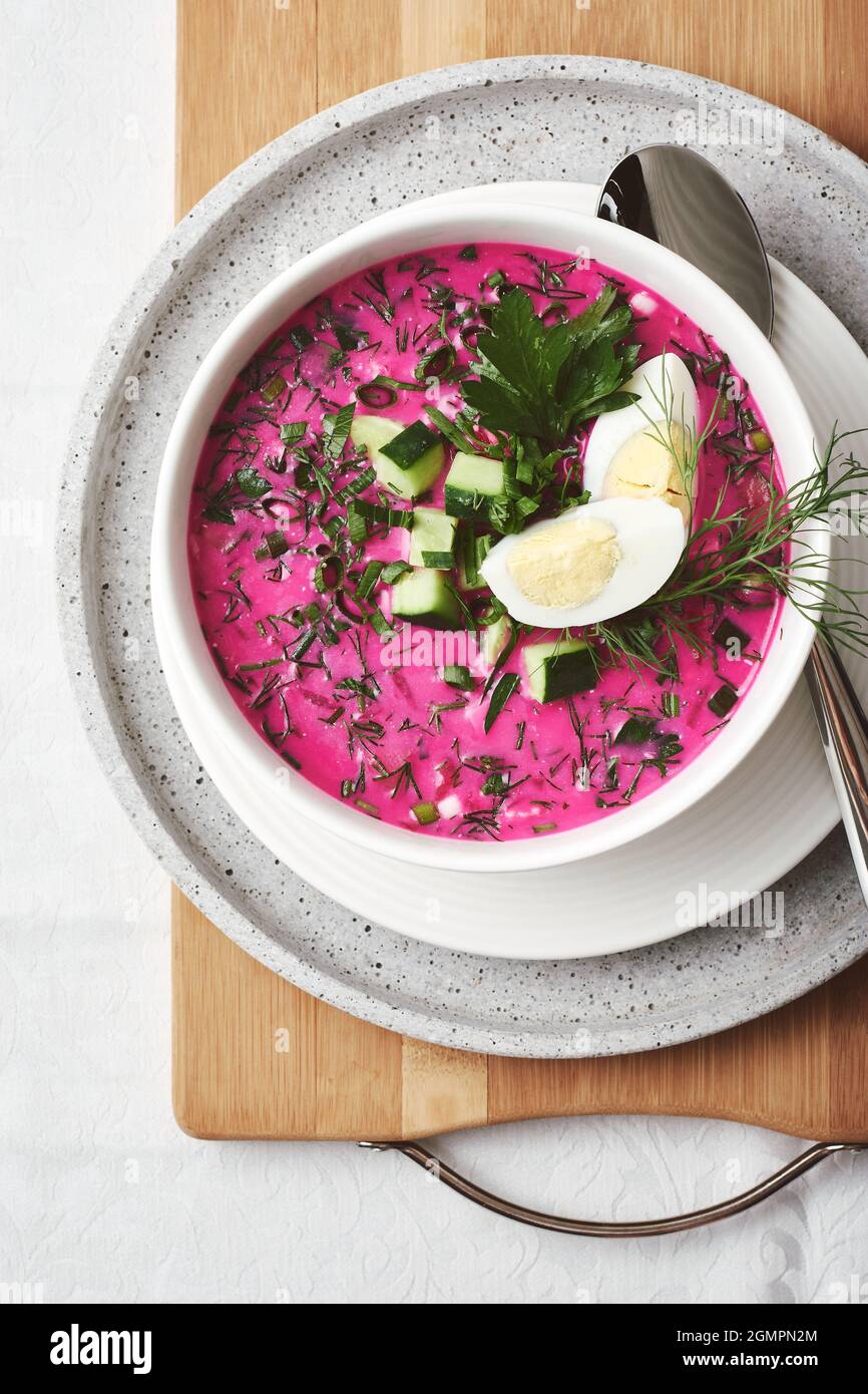 Kalte Rote Beete Suppe mit Gurke, Ei und Kräutern auf einem Tisch. Stockfoto