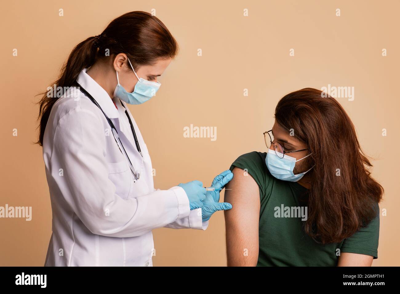 Ärztin in medizinischen Handschuhen und Gesichtsmaske geimpfende Patienten Stockfoto