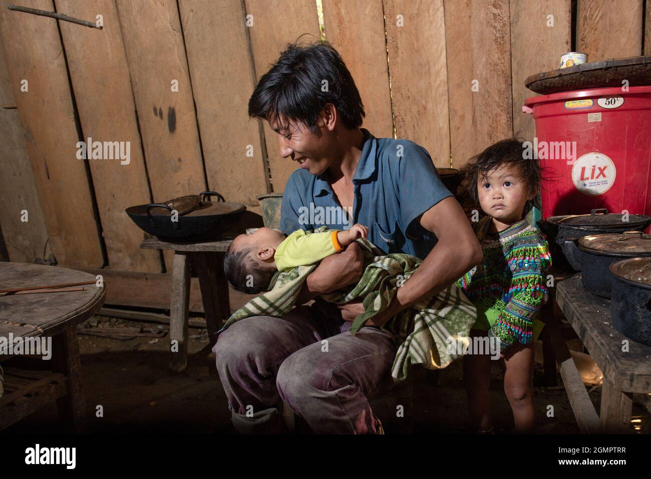 Sapa, Vietnam - 14. April 2016: Vietnamesischer Vater mit Kindern zu Hause, während seine Frau arbeitet. Vaterschaft in Asien, ländliche arme Gegend. Stockfoto