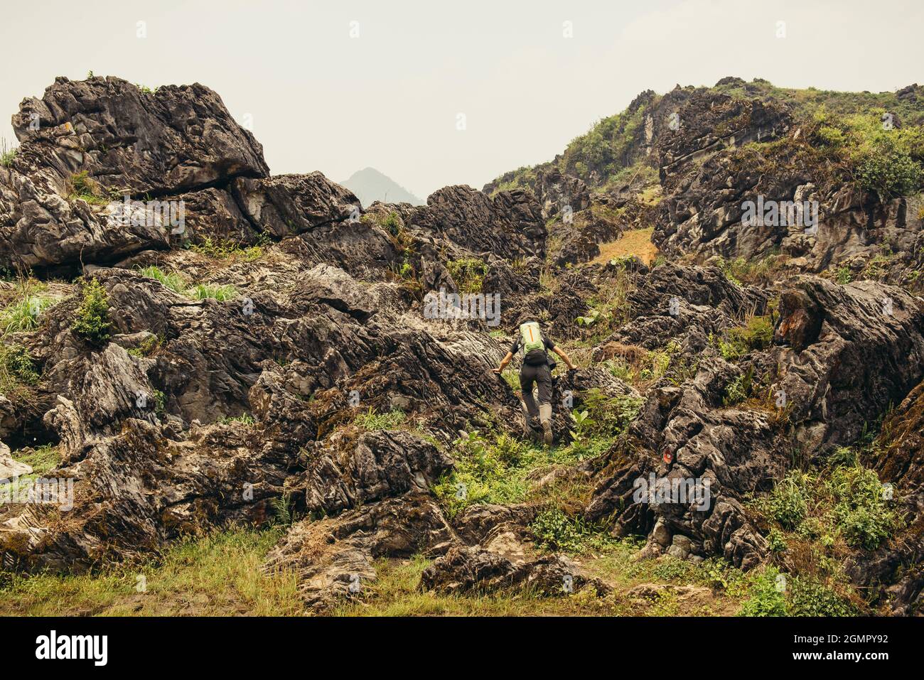 Mann wandern mit Rucksack hoch in den grünen Bergen im Sommer. Landschaftsbeobachtung während einer kurzen Pause. Kopieren Sie Platz am klaren Himmel in Vietnam Stockfoto