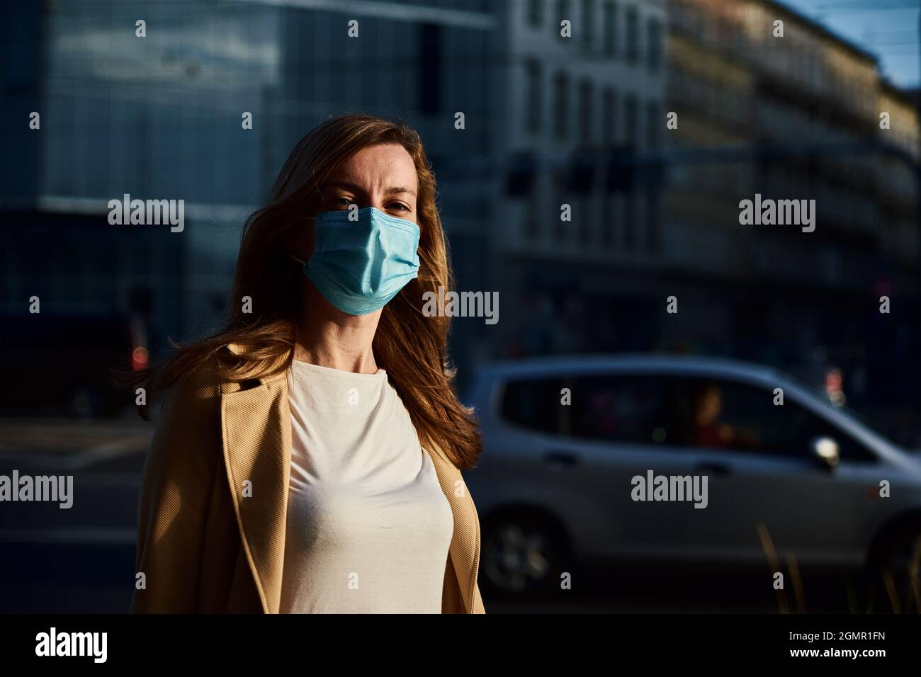 Schöne kaukasische Frau trägt medizinische Schutzmaske in der Stadt Straße. Porträt einer Frau aus dem Tausendjahrtausend. Soziale Distanz und Schutz vor Coronavirus Stockfoto