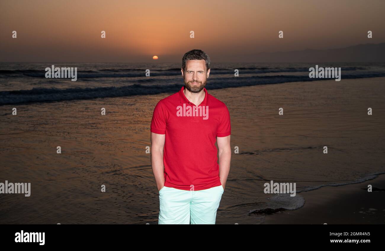 Fröhlicher Mann über dem Meer am sonnigen Sommerstrand, Urlaub Stockfoto