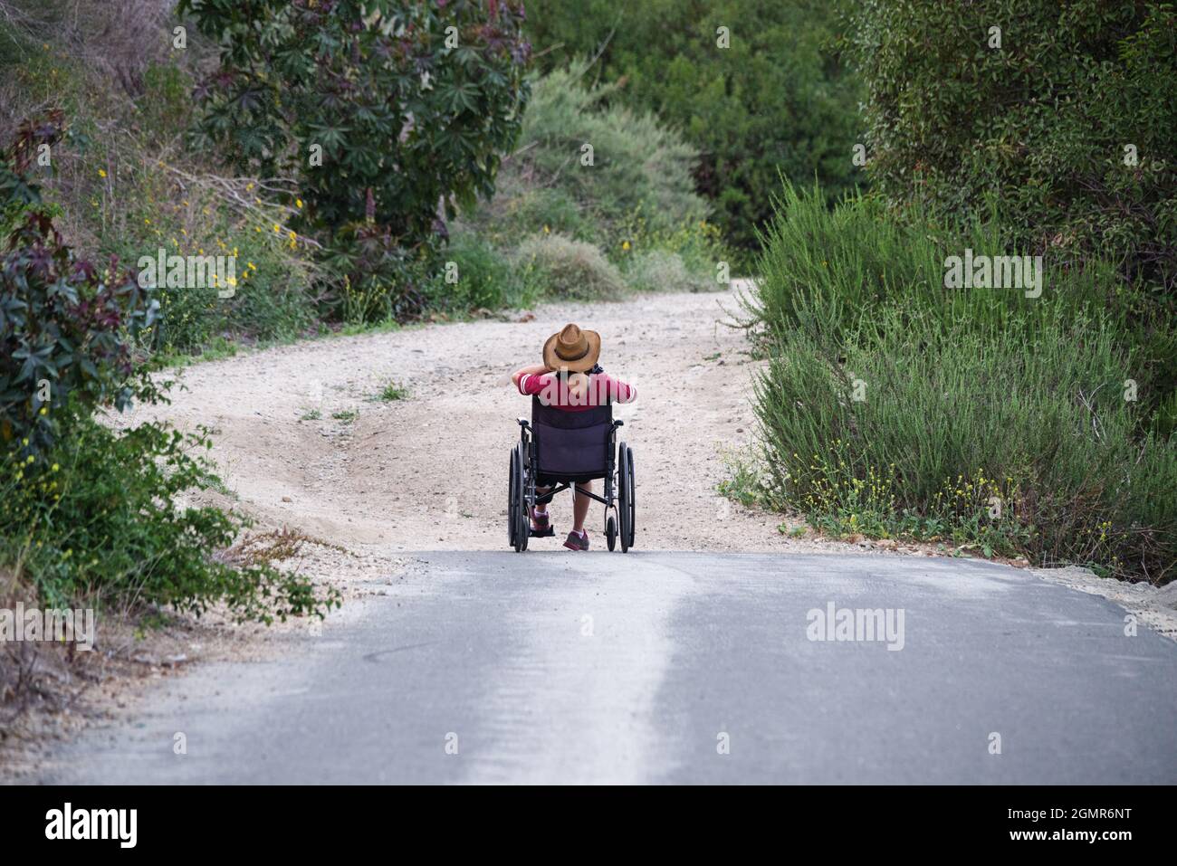 Frau im Rollstuhl am Ende des asphaltierten Weges Stockfoto