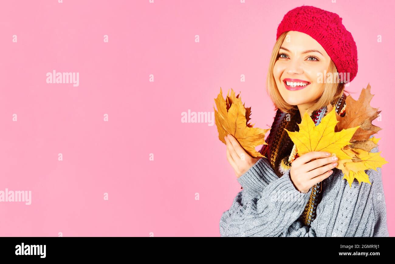 Lächelnde Frau in warmem Pullover, Schal und Hut mit Herbstblättern. Rabatt und Saisonverkauf. Schwarzer freitag. Speicherplatz kopieren. Stockfoto