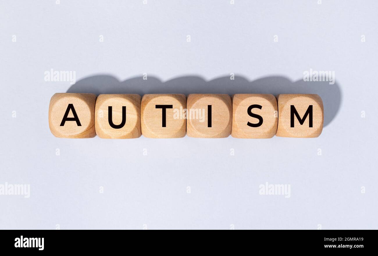 Autismus-Wort auf Holzblock isoliert auf grauem Hintergrund Stockfoto