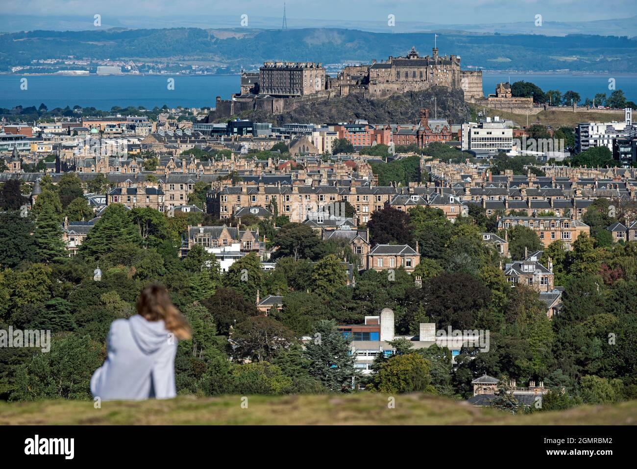 Blick auf das Edinburgh Castle mit einer unscharf dargestellten Figur im Vordergrund, aufgenommen von Blackford Hill, Edinburgh, Schottland, Großbritannien. Stockfoto