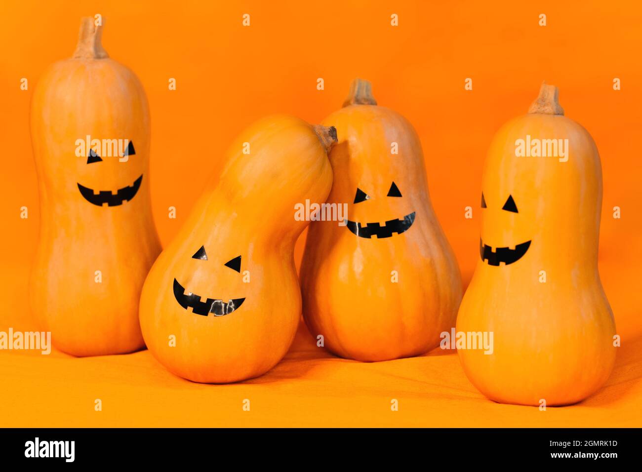 Viel Kürbis mit einem fröhlichen Gesicht an Halloween auf orangefarbenem Hintergrund Stockfoto