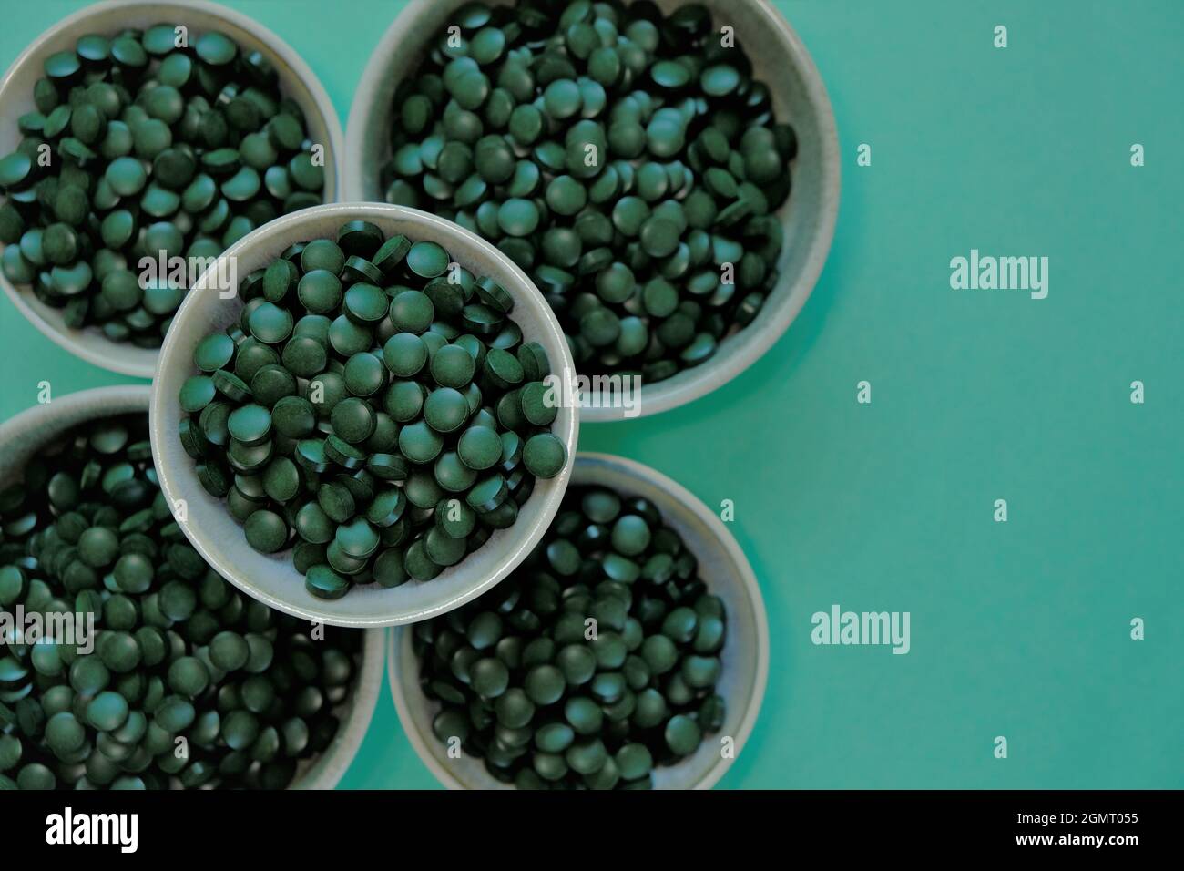 Spirulina Algentabletten. Spirulina Pillen in Tassen auf grünem Hintergrund. Vegetarisches Omega Three.Super Essen Stockfoto