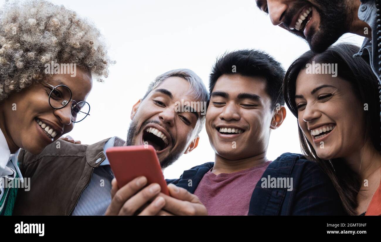 Junge, vielfältige Freunde, die Spaß mit dem Handy im Freien in der Stadt haben - Schwerpunkt auf asiatischem Männergesicht Stockfoto