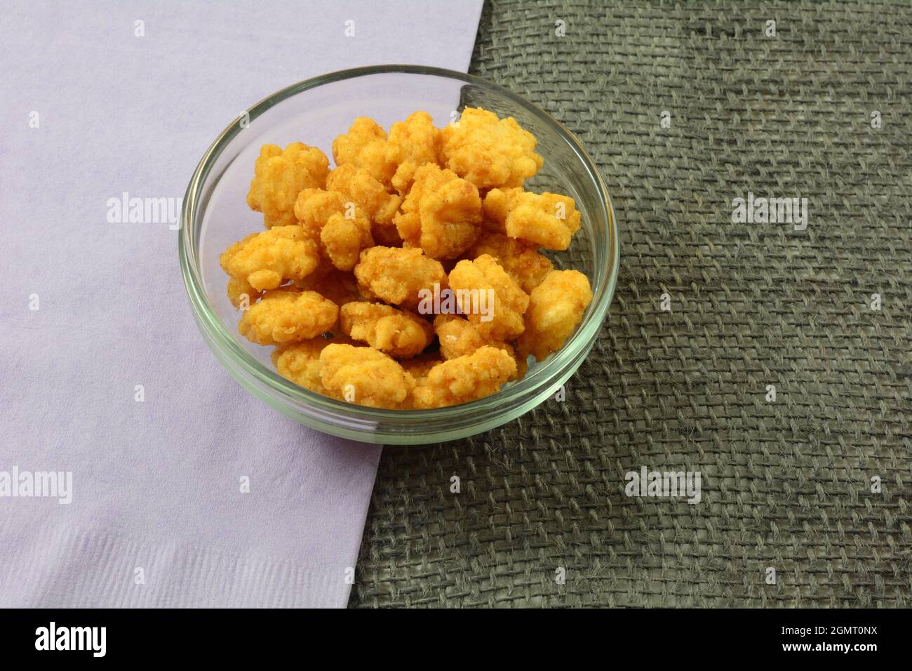 Süße und würzige Reiscracker-Kugeln in Glas-Snack-Schale mit Lavendelserviette Stockfoto
