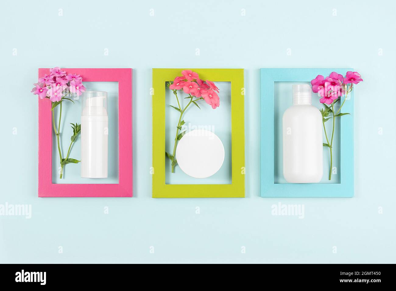 Set von Kosmetika für die Hautpflege Gesicht, Körper, Hände. Weiße leere Kosmetikflasche, Tube, Glas, Blumen in hellen Rahmen auf blauem Hintergrund. Kreative Cosmet Stockfoto