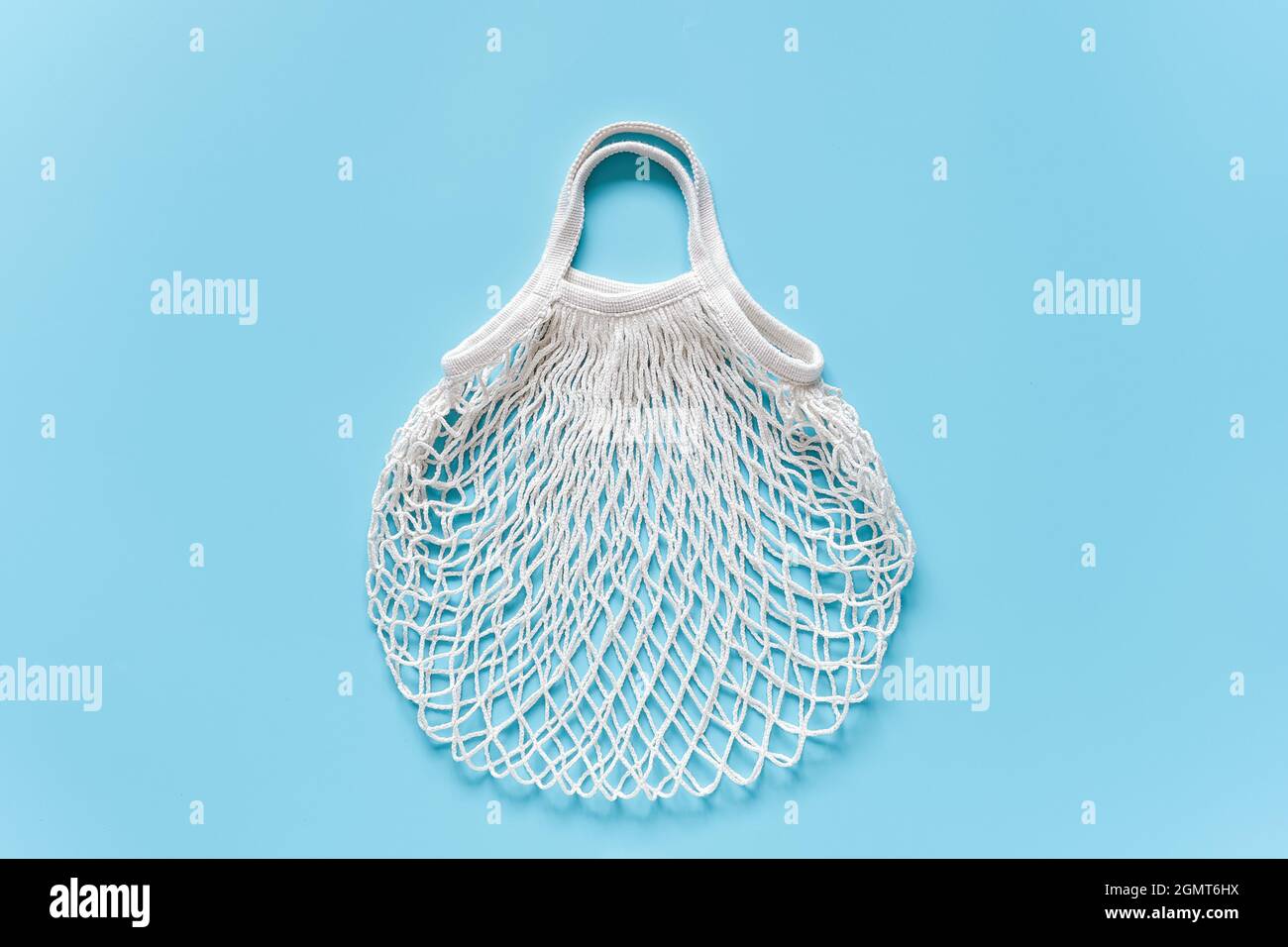 Leere weiße wiederverwendbare Einkaufstasche aus Öko-Mesh auf blauem Hintergrund. Konzept kein Kunststoff, keine Verschwendung und Pflege der Umwelt. Platz kopieren Draufsicht Layout f Stockfoto