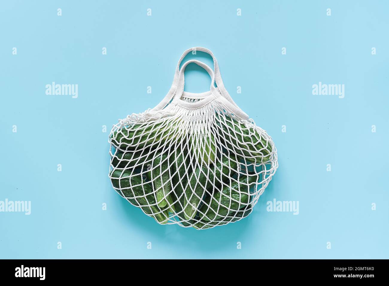 Frische grüne Gurken Gemüse in wiederverwendbaren Shopping Öko-frendly Mesh-Tasche auf blauem Hintergrund. Konzept kein Kunststoff und kein Abfall. Platz kopieren Draufsicht Stockfoto