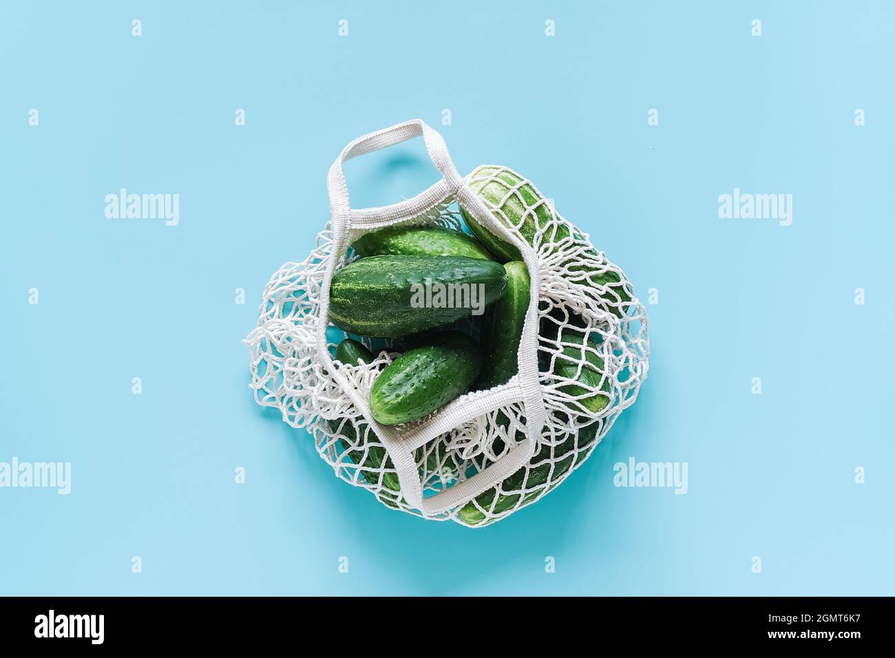 Frische grüne Gurken Gemüse in wiederverwendbaren Shopping Öko-frendly Mesh-Tasche auf blauem Hintergrund. Konzept kein Kunststoff und kein Abfall. Platz kopieren Draufsicht Stockfoto