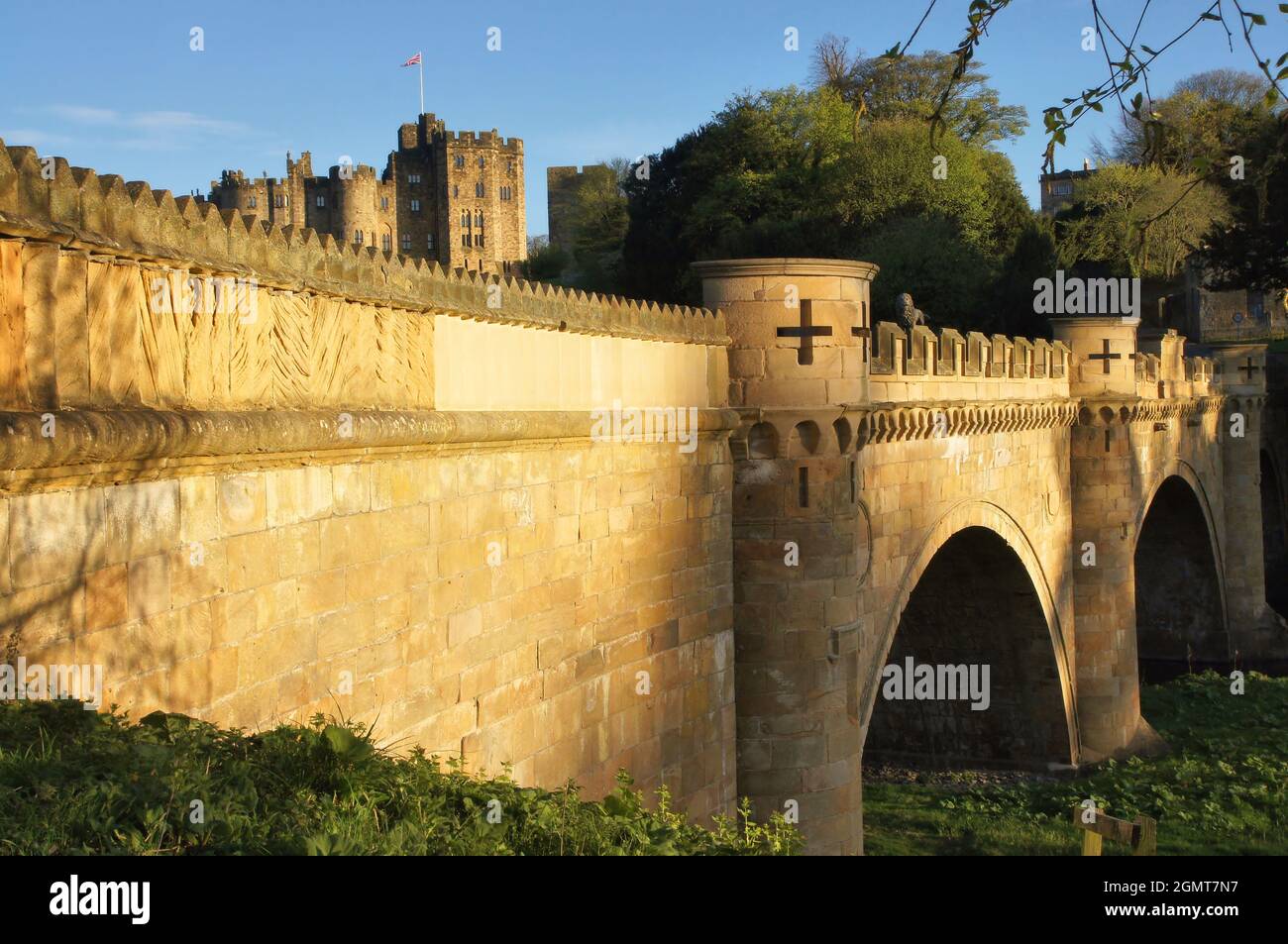 Die Lion Bridge über den Fluss Aln und Alnwick Castle glühend Gold kurz vor Sonnenuntergang in Alnwick, Northumberland, England Stockfoto