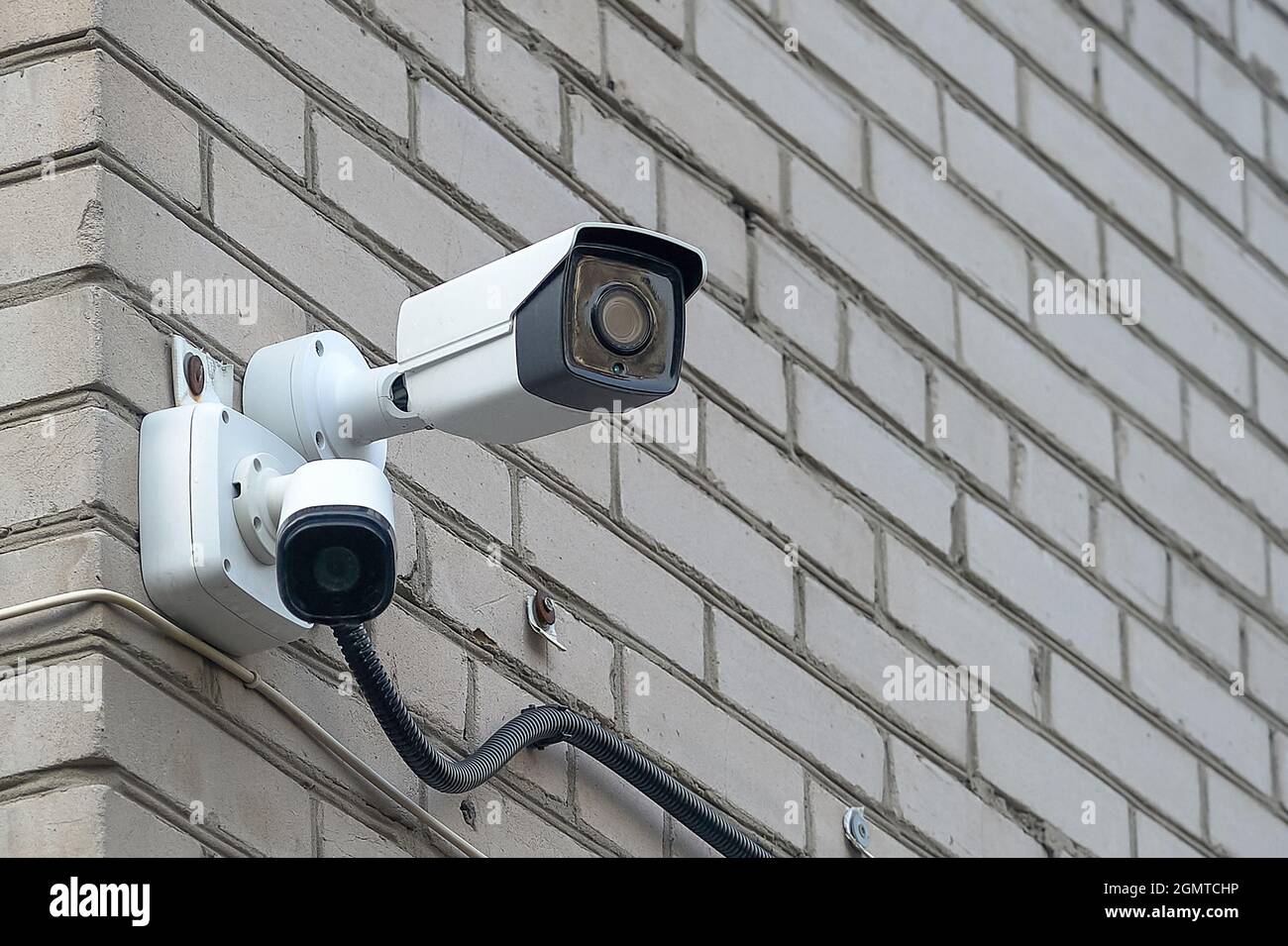Die CCTV-Kamera hängt an der Ziegelwand des Hauses Stockfoto