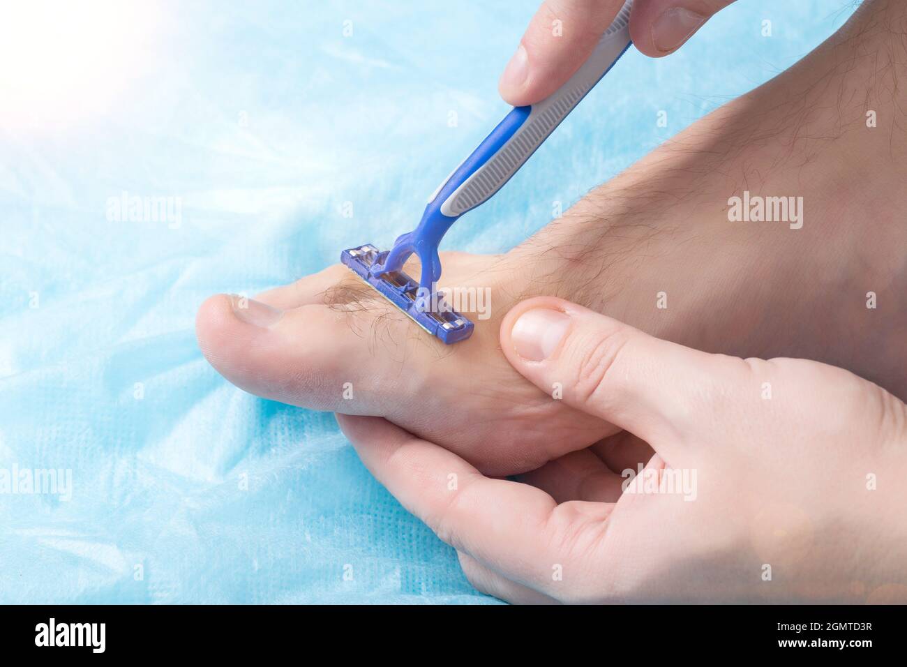 Ein Mann hält einen Rasierer in der Nähe seiner Zehen, wo die Haare wachsen.  Konzept zum Rasieren von Haaren an Beinen und Zehen, Epilieren  Stockfotografie - Alamy