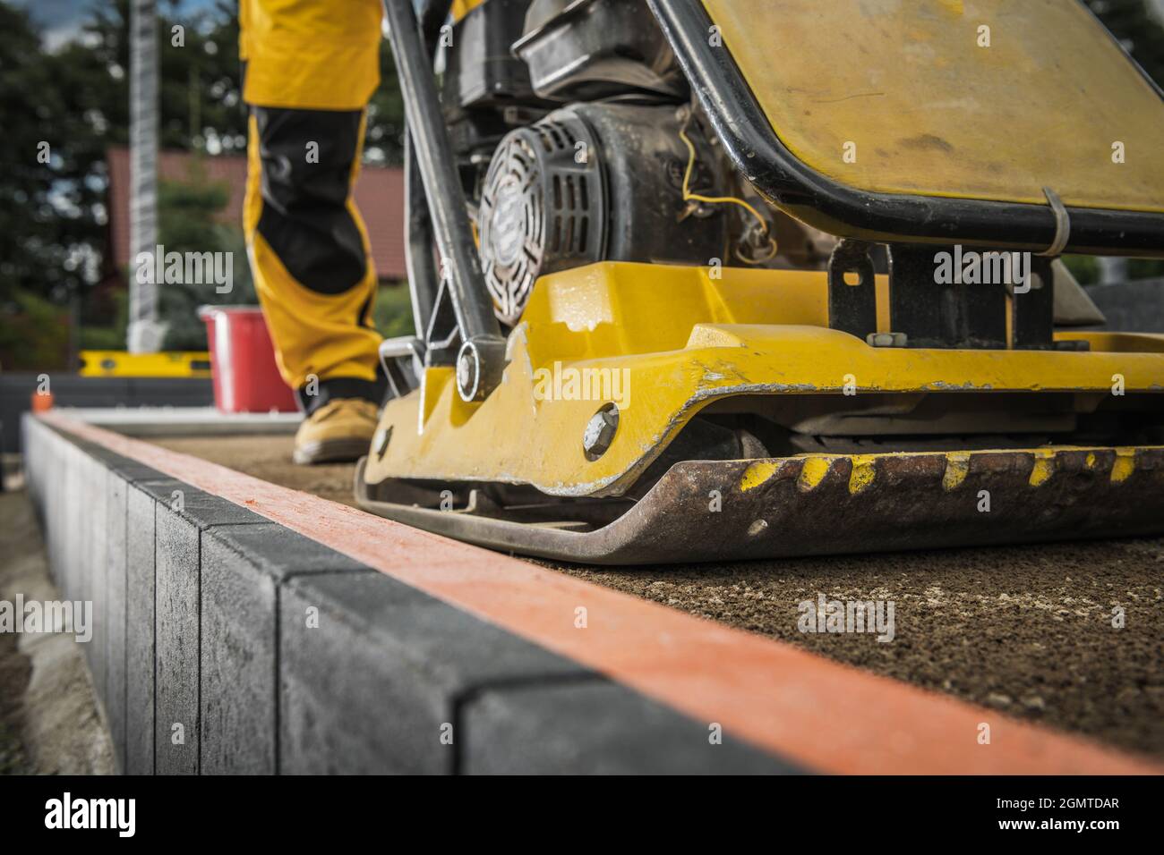 Arbeiter mit Bodenkompktor Vorbereitung Boden für die Pflasterung. Robuste Baumaschinen. Stockfoto