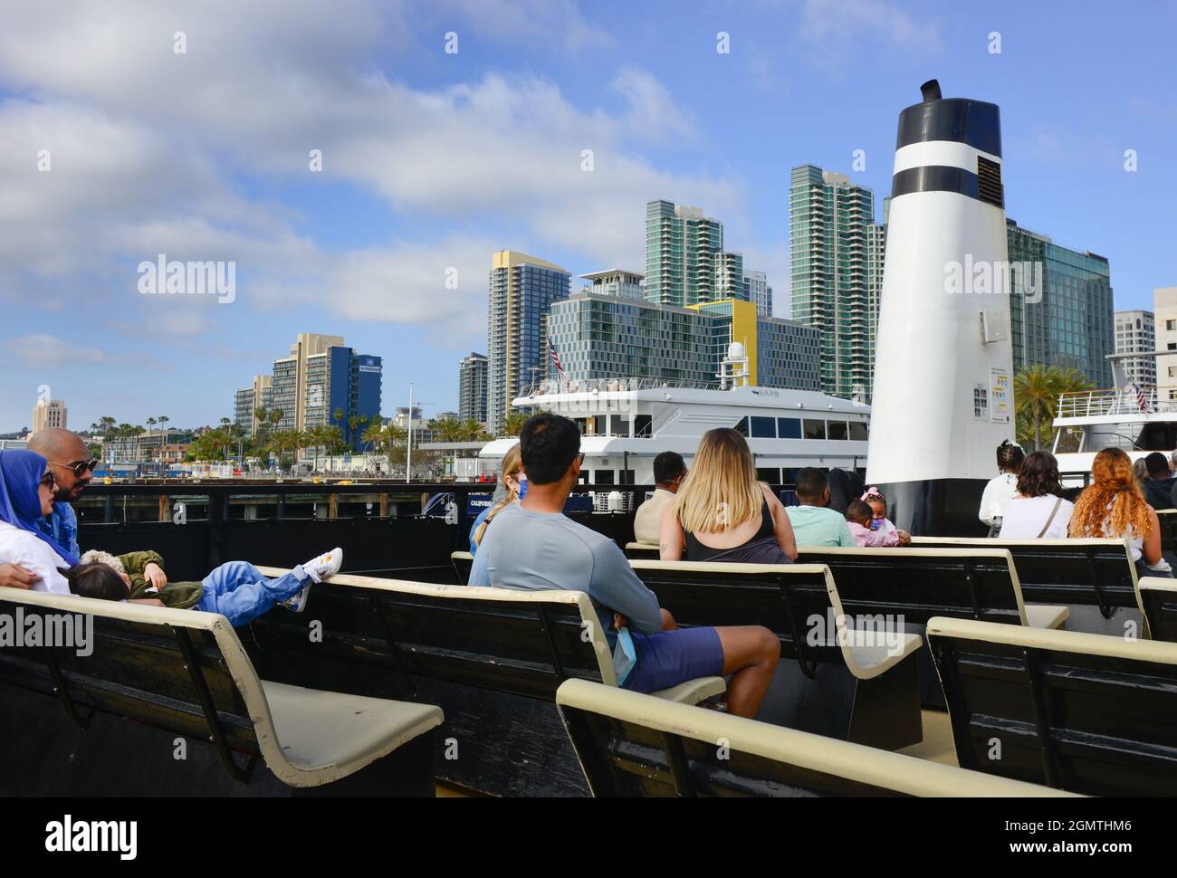 Rückansicht der Passagiere auf dem Open-Air-Deck des Cabrillo, der San Diego Ferry, mit Anlegestelle im modernen Skyline-Hintergrund, San Diego, CA Stockfoto