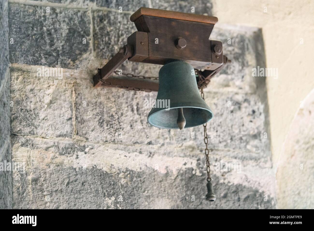Alte Glocke hing an einer Steinmauer Stockfoto
