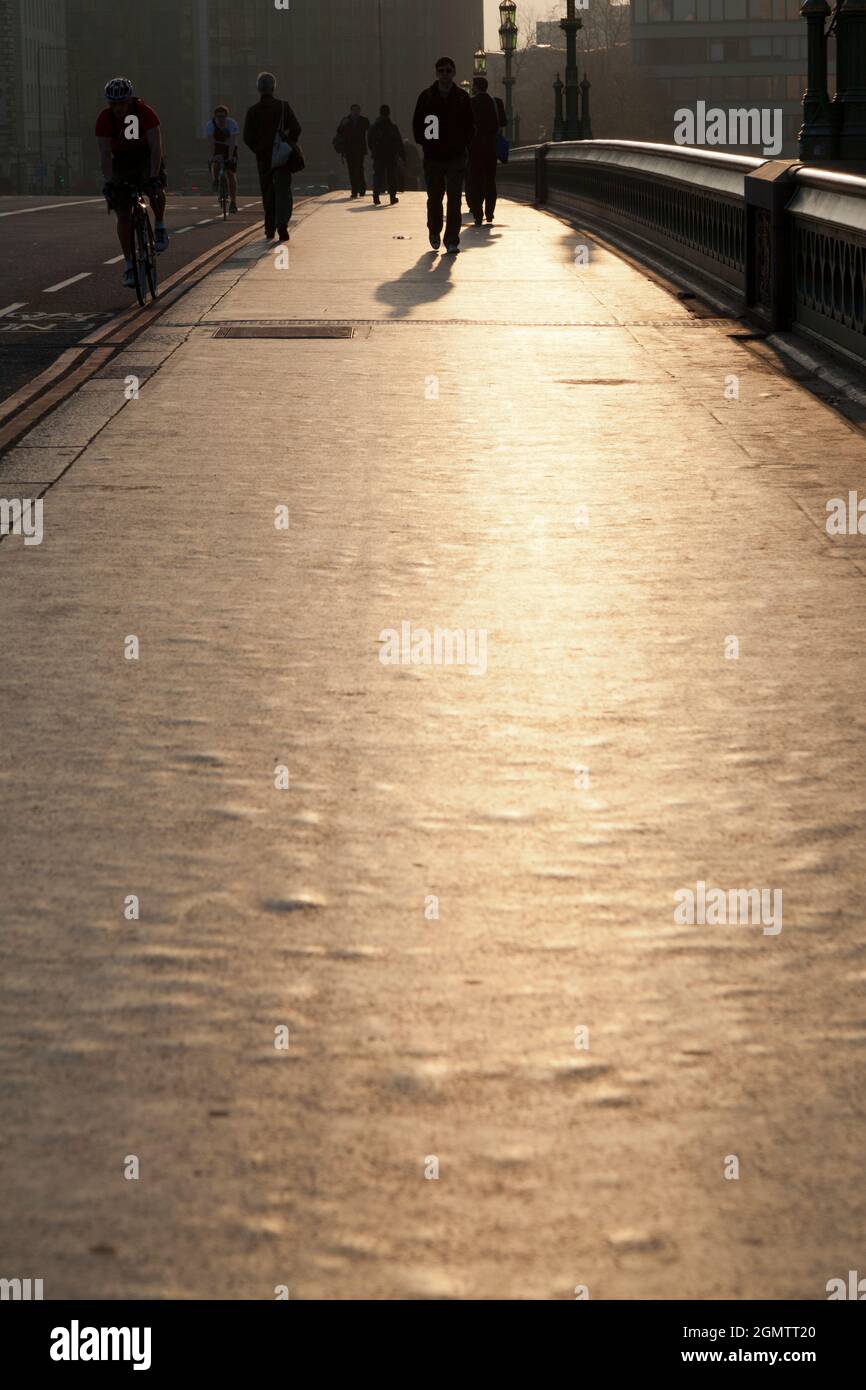 London, England - 2012; Verloren in einer eigenen Welt - während alle vorbeirauschen. Pendler im Morgengrauen auf der Westminster Bridge, London. Stockfoto