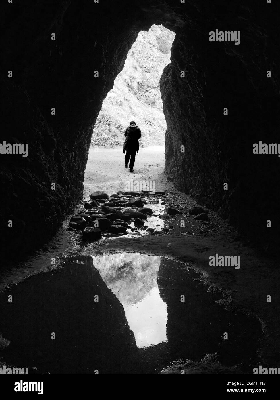 County Antrim, Nordirland - 9. Juni 2017; ein einsame Tourist spaziert aus den Cushendun Caves Cushendun ist ein hübsches kleines Küstendorf in der Grafschaft Stockfoto