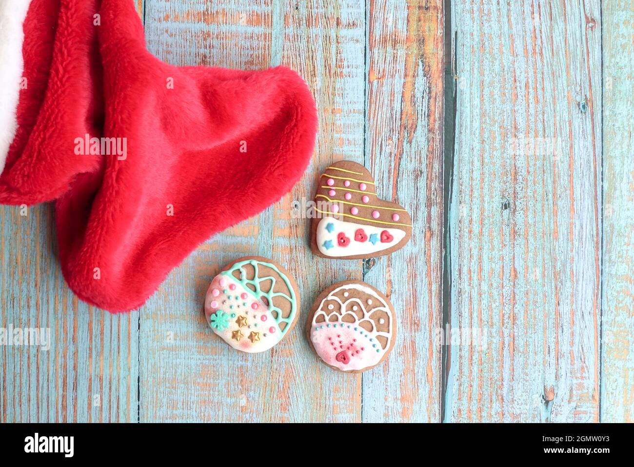 Gingebrot-Kekse auf einem Holztisch mit weihnachtsmann-Socke an der Seite. Draufsicht. Stockfoto