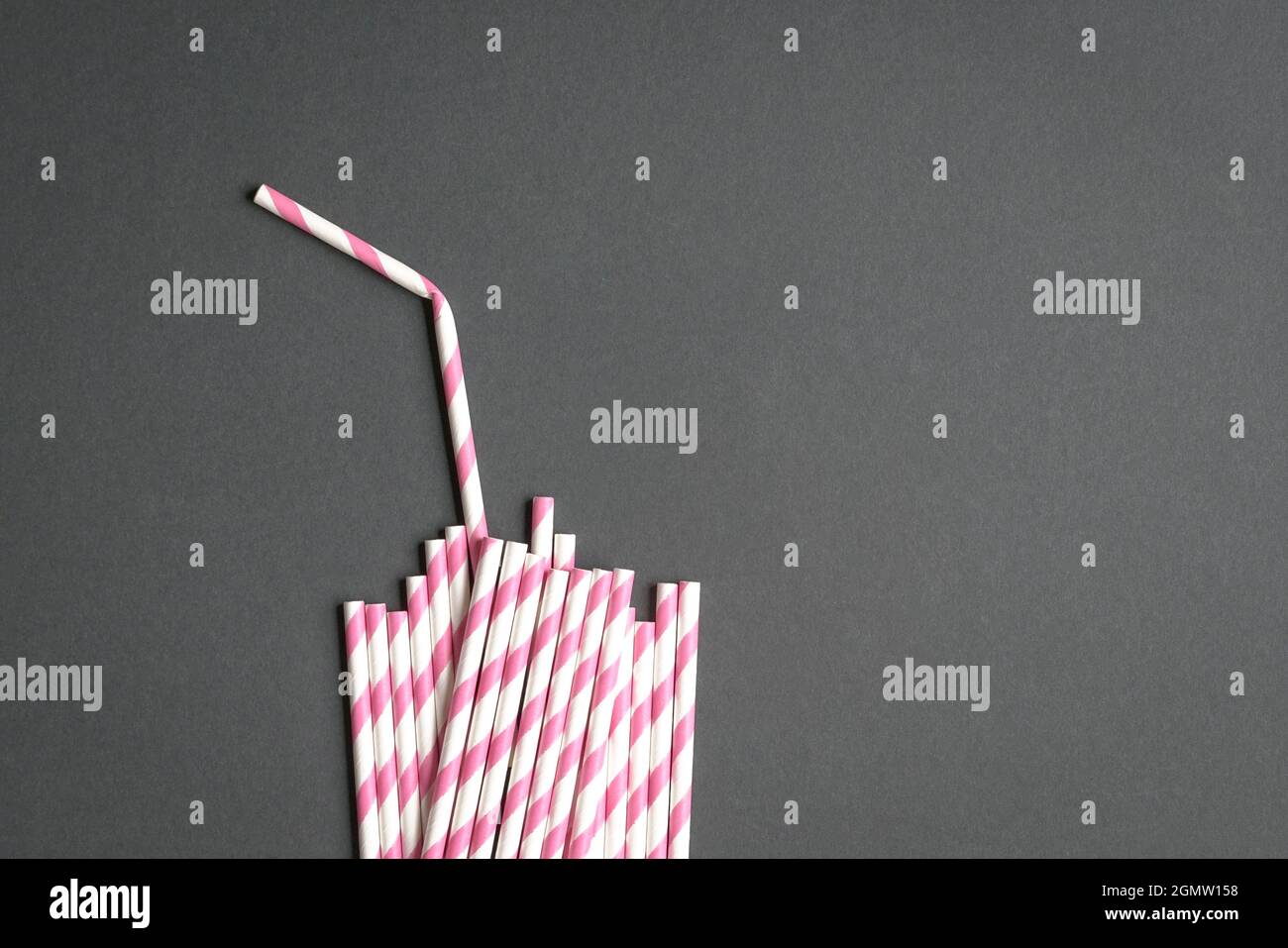 Glas mit Stroh aus Papierhalmen auf schwarzem Hintergrund. Party oder kein Plastikkonzept. Stockfoto