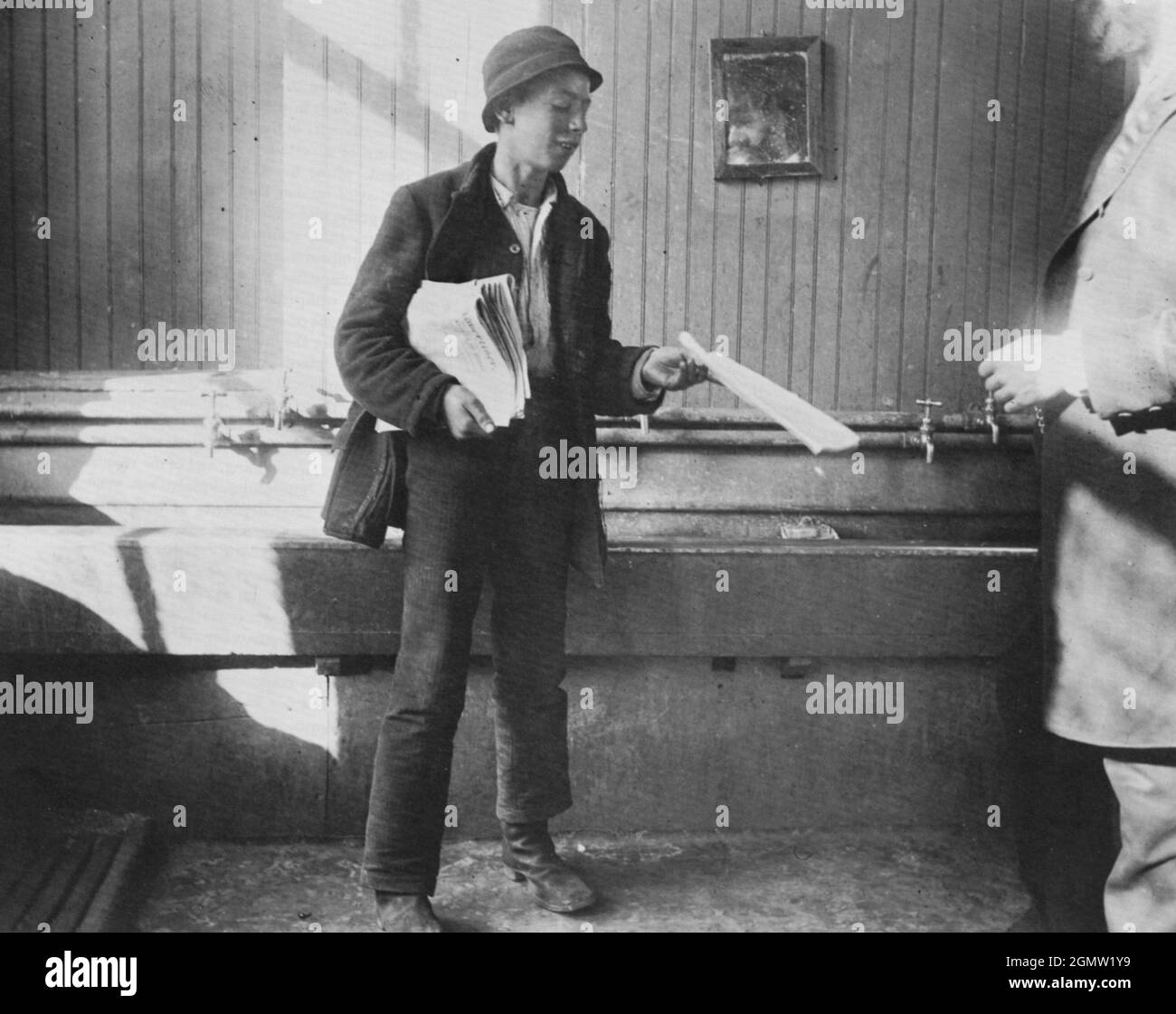 Jacob Riis Fotografie - Newsboy im Wohnhaus in der Duane Street - Newsbo, der seinen Handel mit Zeitungsverkäufen ausschauft - sinkt im Hintergrund. Stockfoto