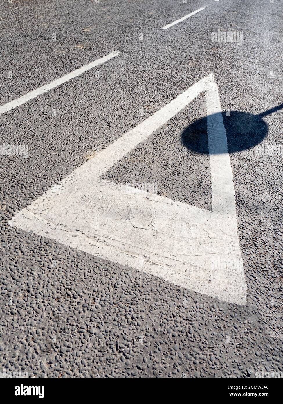 Radley Village, Oxfordshire, England - 5. März 2021; Keine Menschen im Blick. Reine Geometrie - Straßenschilder und der Schatten eines verflechten sich auf einer Fahrspur in h Stockfoto