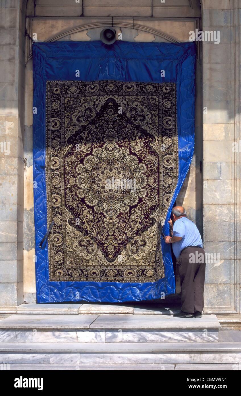 Konya, Türkei - 2003. Juni; Mann guckt an einem Teppich vorbei in eine Moschee in Konya, Zentraltürkei. Peekaboo Stockfoto