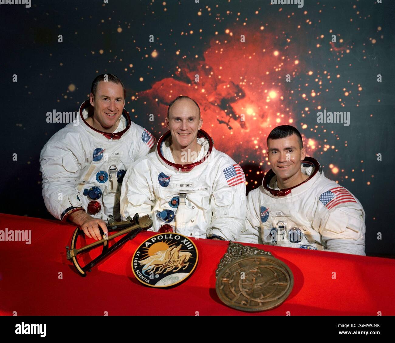 (Dezember 1969) --- die Mitglieder der Hauptmannschaft der Apollo 13 Mondlandemission (von links nach rechts) sind die Astronauten James A. Lovell Jr., Kommandant; Thomas K. Mattingly II, Kommandomodulpilot; und Fred W. Haise Jr., Mondmodulpilot. Sie sitzen vor einer Szene des Lagunennebels, mit den Missionsinsignien und zwei Objekten der frühen Navigation im Vordergrund. Im Apollo 13 Emblem (Mitte) ist Apollo, der sonnengott der griechischen Mythologie, dargestellt, der symbolisiert, dass die Apollo-Flüge das Licht des Wissens auf die ganze Menschheit erweitert haben. Der lateinische Satz Ex Luna, Scientia bedeutet 'fro Stockfoto