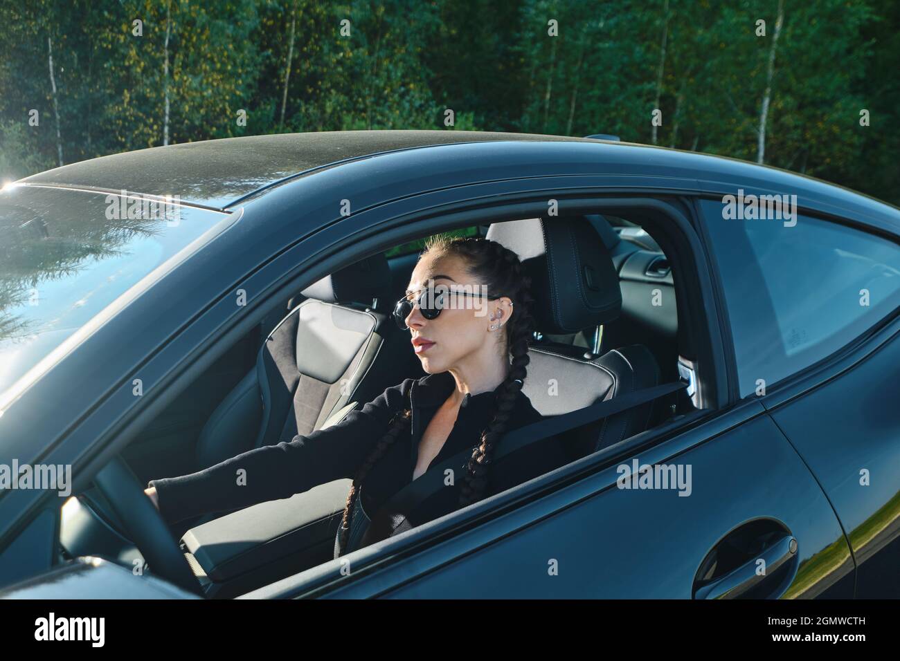 Seriöse junge Frau, die auf einer Landstraße ein kraftvolles Auto fährt Stockfoto