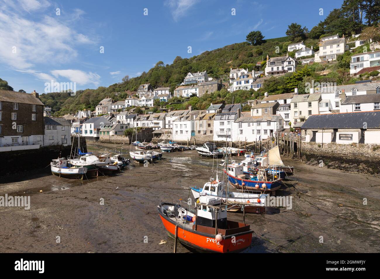 Angeln und Vergnügungsboote bei Ebbe im Hafen von Polperro, Cornwall, mit malerischen, hauptsächlich weiß gestrichenen Häusern des Dorfes im Hintergrund. Stockfoto