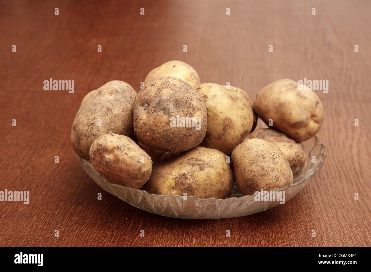 Teller mit rohen Kartoffeln auf dem Tisch. Tageslicht im Innenbereich Stockfoto