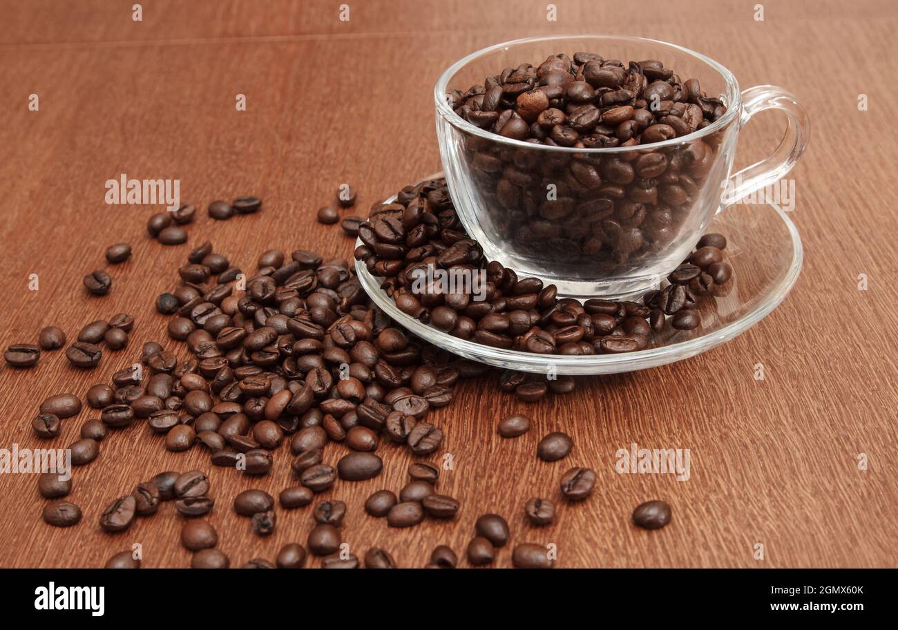 Kaffeebohnen in einer Tasse auf einem Holztisch. Nahaufnahme im Innenbereich Stockfoto