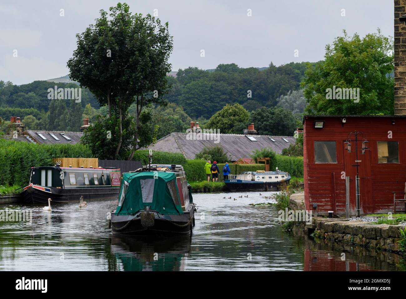 Rot & grün Schmalboot Segeln (Reisen auf semi-städtischen Wasserstraßen) Boote an Kanalenanlegestellen & Schlepptau Wanderer - Leeds Liverpool Canal, England, Großbritannien. Stockfoto