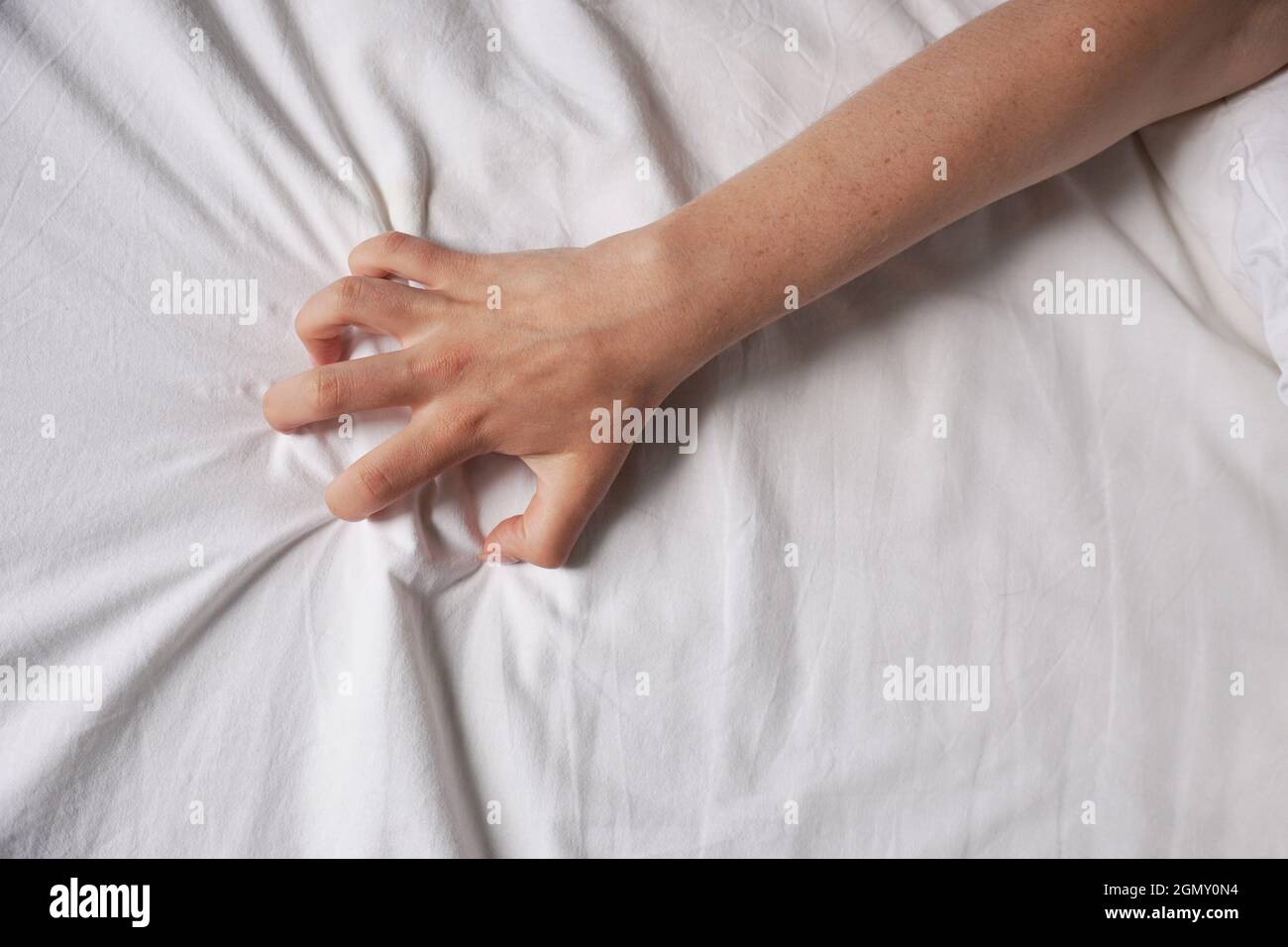 Weibliche Hand greift nach Bettlaken Stockfoto